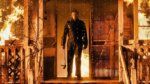 killer michael myers standing on porch of burning house