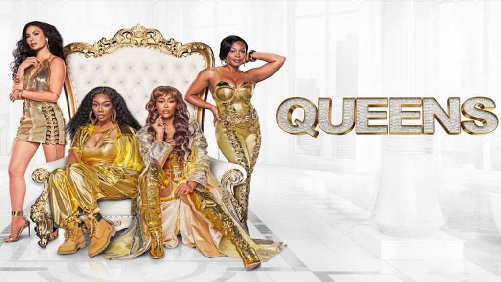 4 women in gold outfits on throne with Queens logo