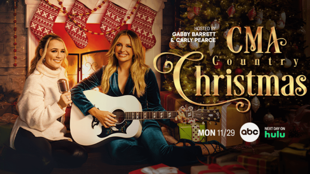 Gabby Barrett and Carly Pearce in front of a fire with a guitar and stockings