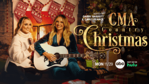 Gabby Barrett and Carly Pearce in front of a fire with a guitar and stockings
