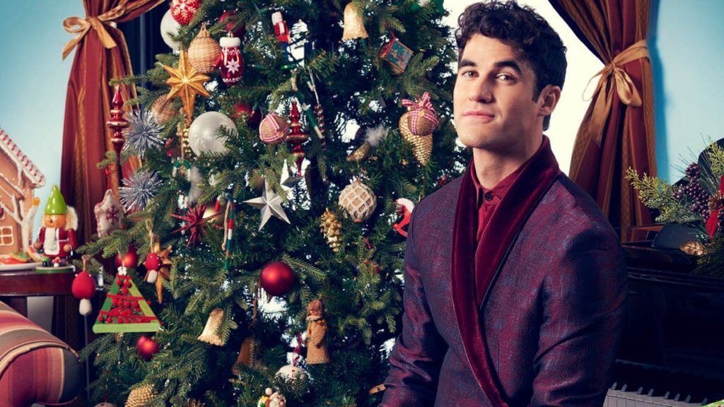 Darren Criss in front of a Christmas tree