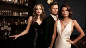 Three leads of Dynasty looking glamours and leaning on a bar
