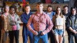 Central cast of Letterkenny standing in front of a bar