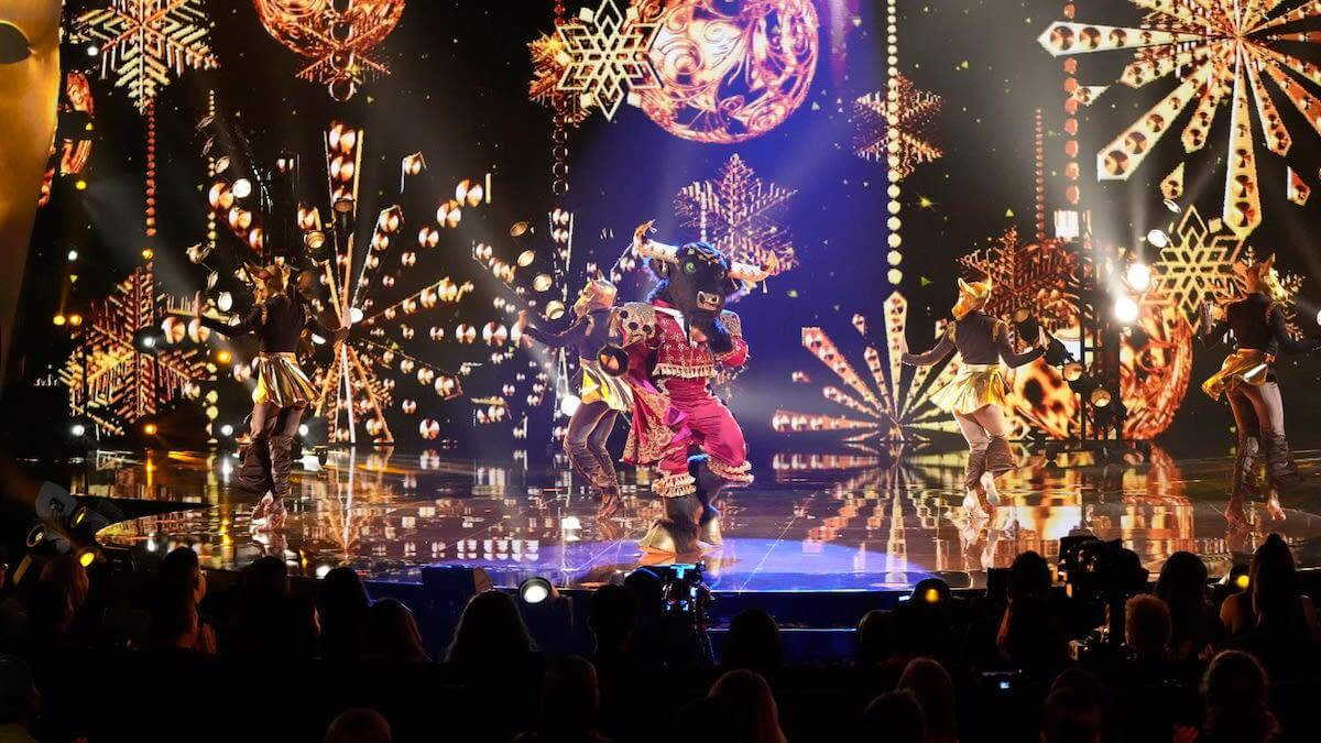 singer dressed in bull matador costume on stage with gold holiday ornaments