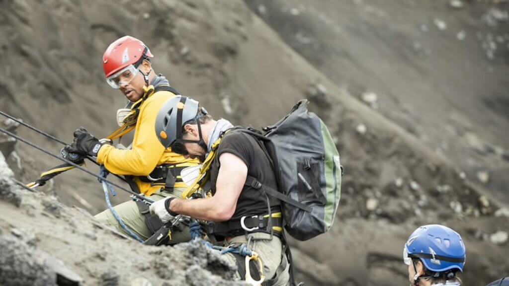 Will Smith in climbing gear with explorer on side of volcano