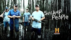 A group of men holding rifles stand in a swamp