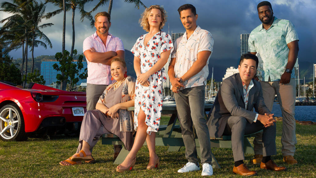 The cast of Magnum PI on a tropical location with a red sports car