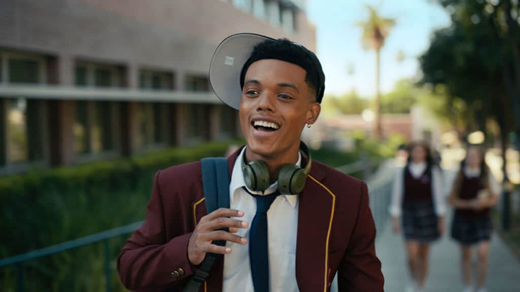 A young black man in a preppy school uniform and sideways cap