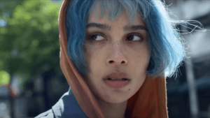 A woman with blue hair looks over her shoulder