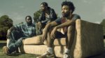 The cast of Atlanta sitting on a couch outside