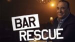 A gentleman looks at the camera sitting at a bar