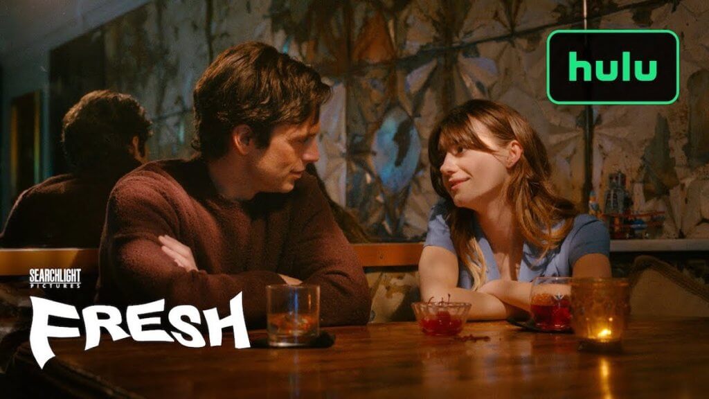 A couple look at each romantically in a candlelit restaurant