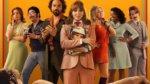 A group of people in 1970s clothes looking at a nude male model