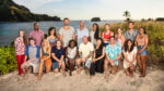 A group of Survivor competitors sit on a beach