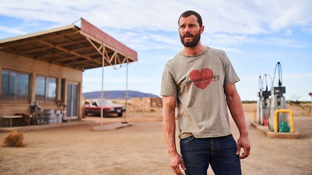 A man stands in front of a desolate gas station in the Australian outback