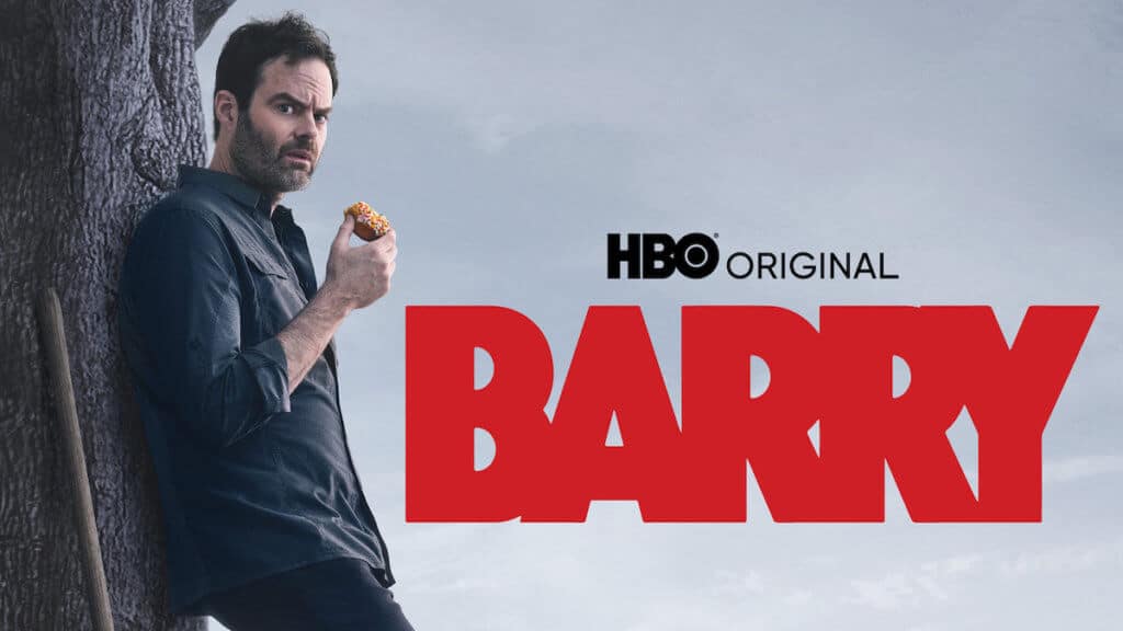 A man with a shovel leans against a tree eating a donut