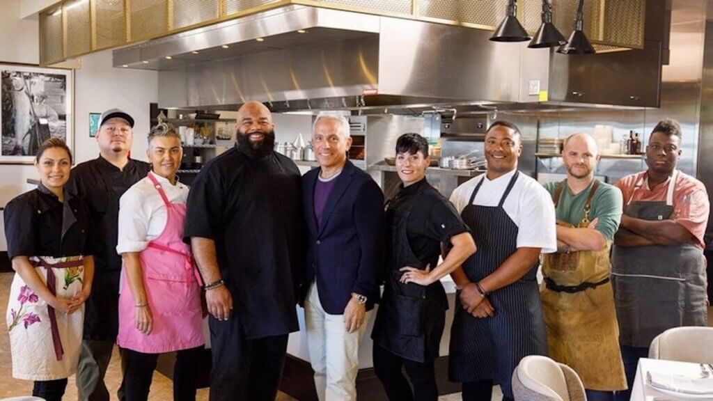 Host and contestants of Big Restaurant Bet in a kitchen
