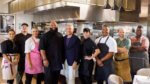 Host and contestants of Big Restaurant Bet in a kitchen