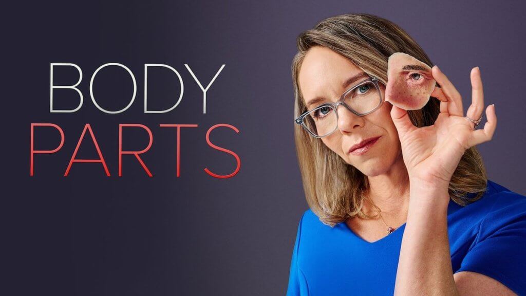 A woman holds up a replica of a part of a face