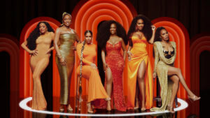 Six fashionable women in elegant dresses in fire colors in front of three red glowing disco arches
