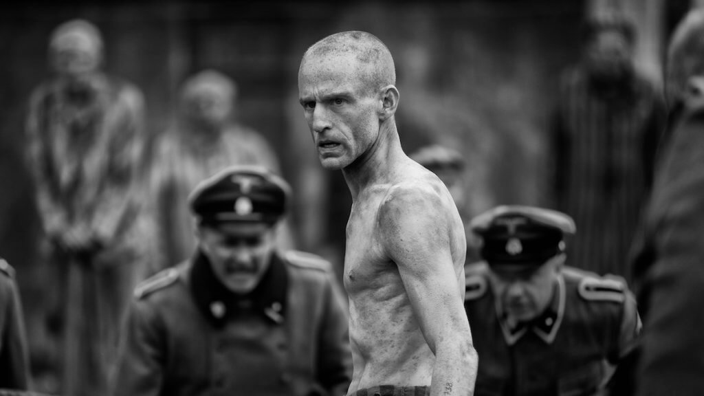 An emaciated man in a boxing circle surrounded by Nazis