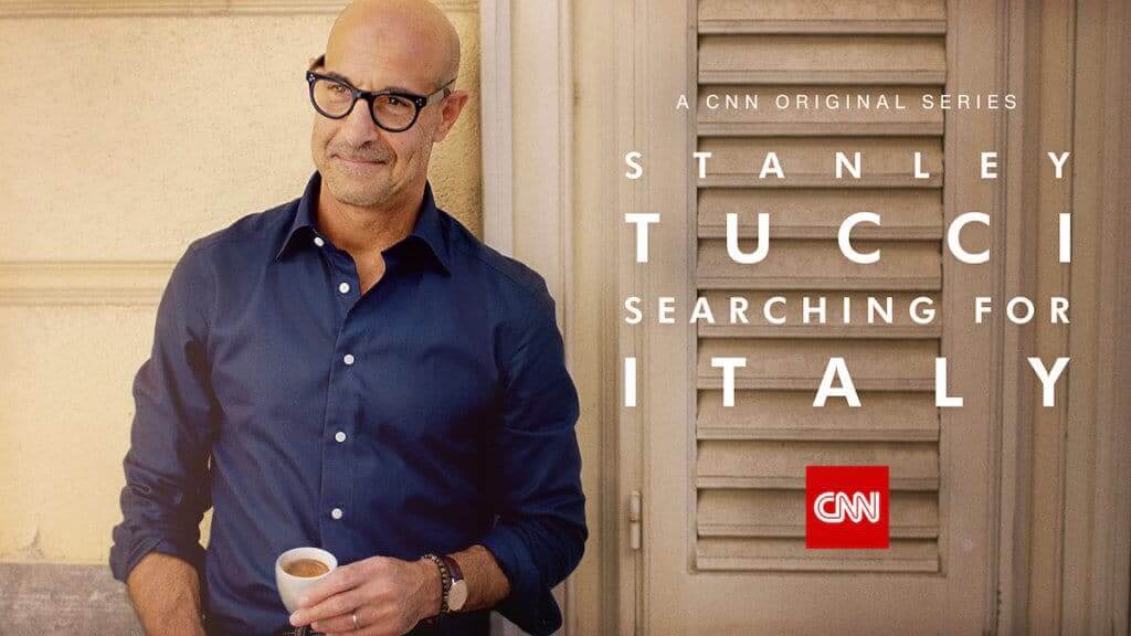 Actor Stanley Tucci leaning on a wall with an espresso cup