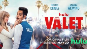A valet looks over his shoulder at the camera with a blonde staring at him and camera flashes going off