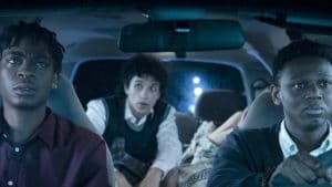 Three friends in a car at night looking nervous