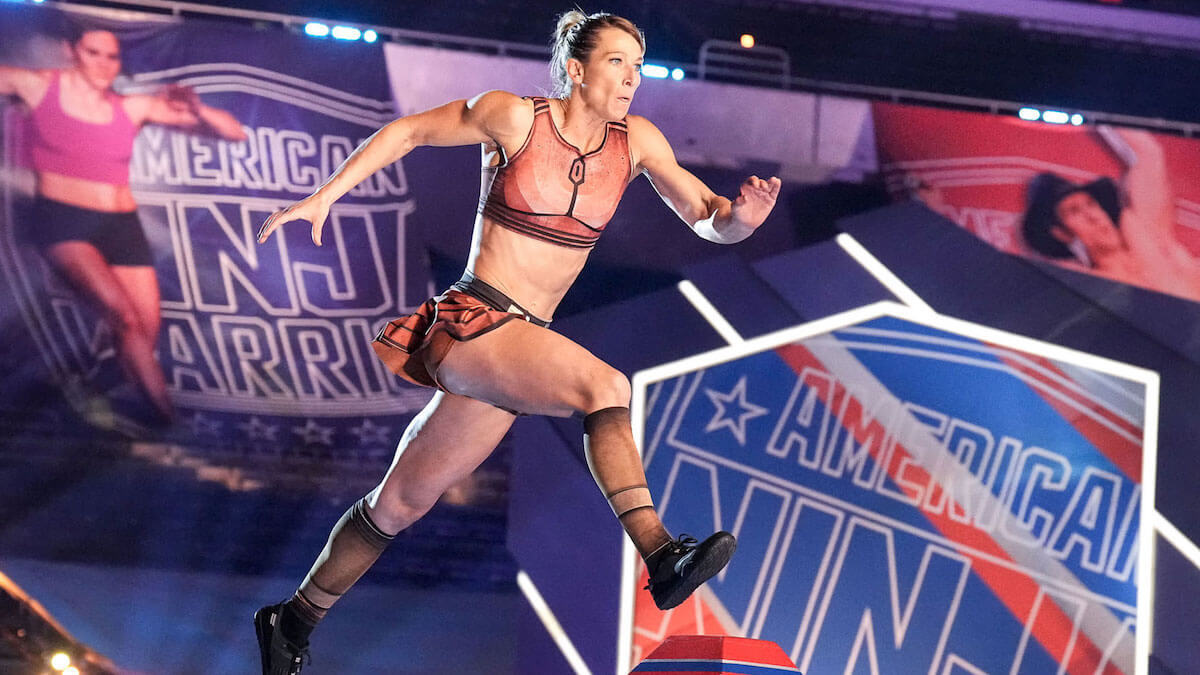 A slim fit woman leaping over an obstacle in the mega course of American Ninja Warrior