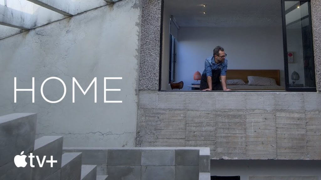 A man leaning through a window in a concrete modern home