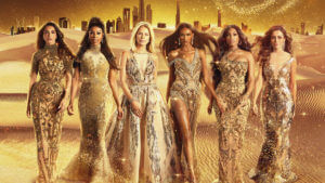 A group of women in gold dresses with the Dubai skyline behind them