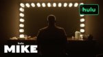 A man in silhouette in front of a mirror with stage lights
