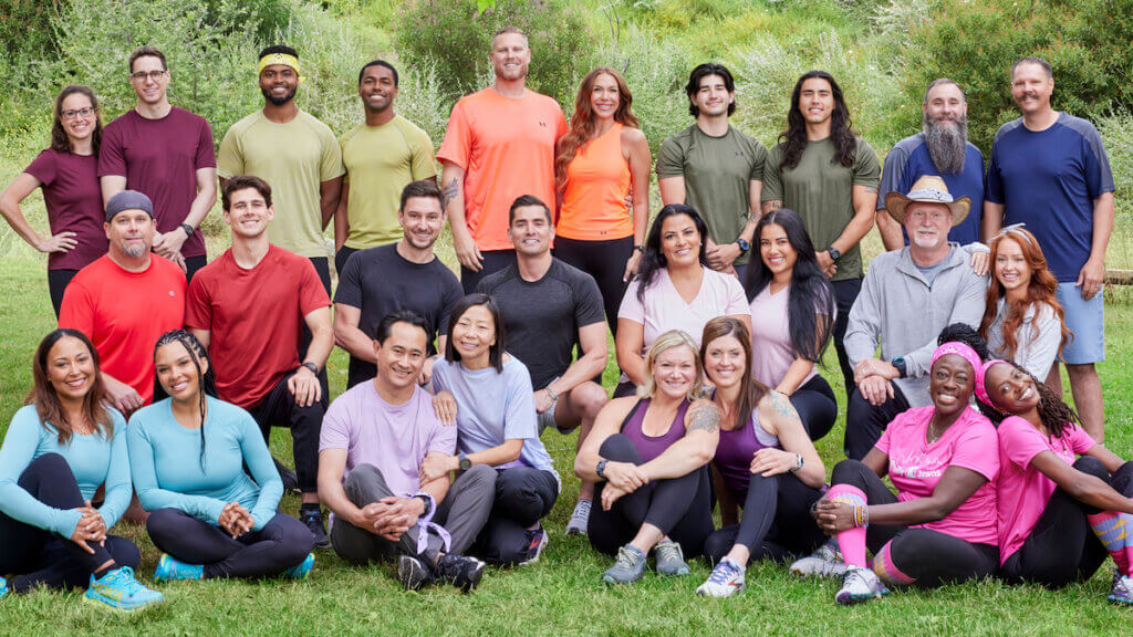 13 pairs of competitors in solid colored tee shirts pose in a group