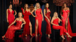 A group of seven women in elegant red gowns
