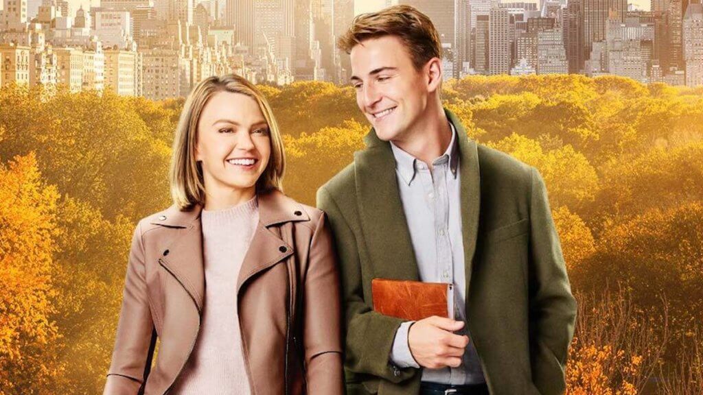 Young man and woman in front of autumn trees and NYC skyline