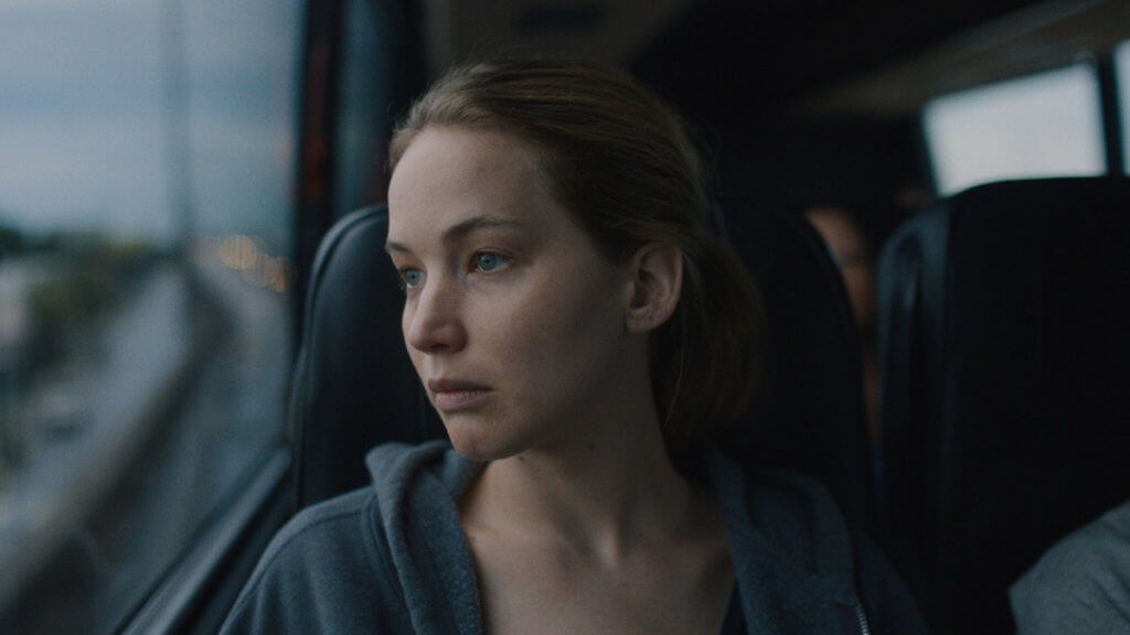 A young woman looking desolately out a bus window