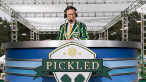 Stephen Colbert behind a sports desk with an announcer's headset on