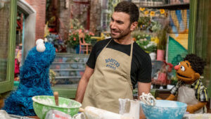 Brett Goldstein baking cookies with two Sesame Street characters