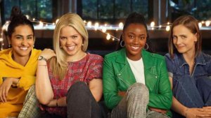 Four college-age friends lined up on a patio sofa