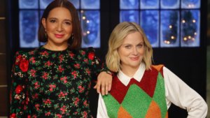 Two female celebrities in holiday clothes and a snowy window behind them