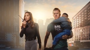 Two missing persons officers walking through a city carrying a young boy.