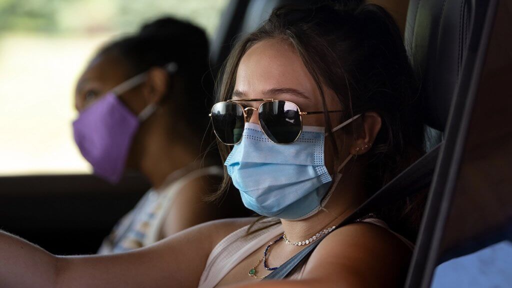 Two girls in a car wearing masks