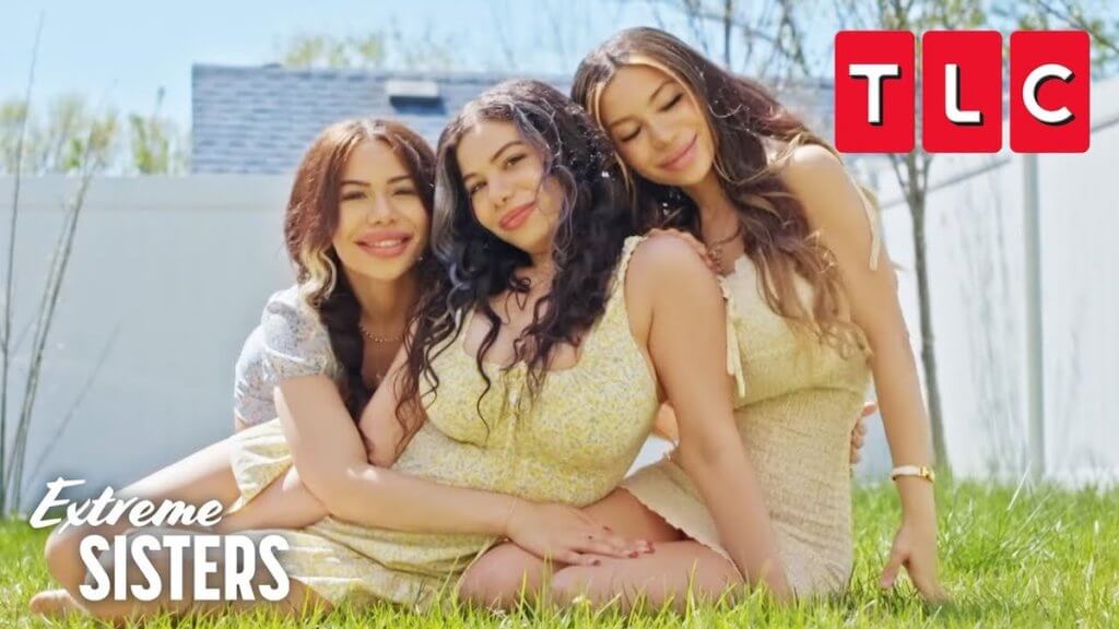 A trio of very similar sisters hugging on a grassy lawn