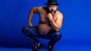 Comedian Bert Kreischer crouching wearing fancy pants and no shirt