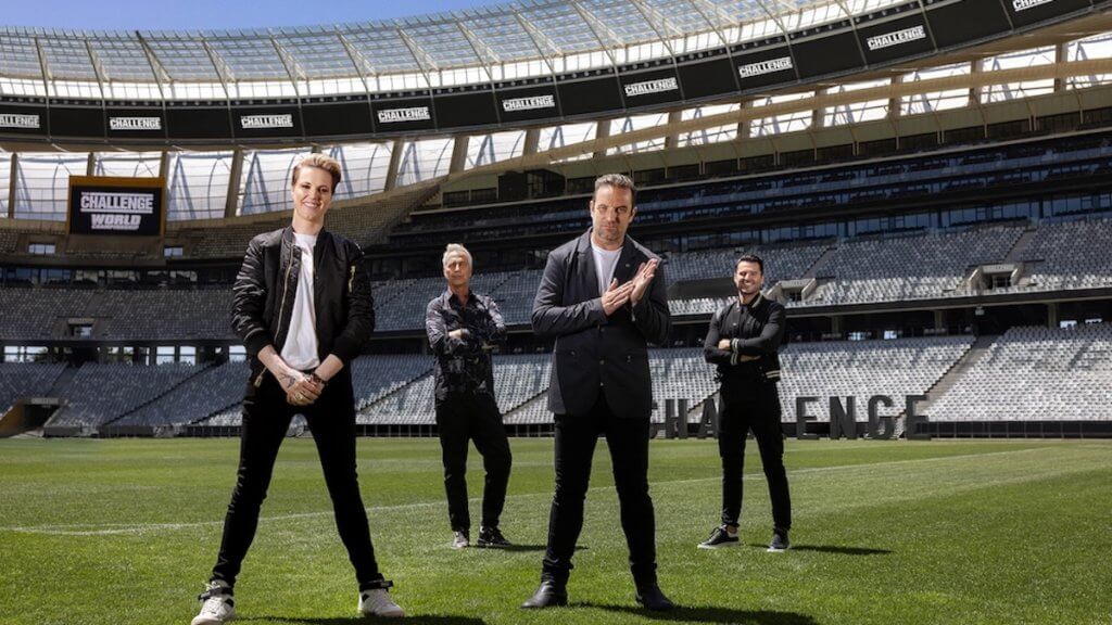 Four athletic judges stand on a large stadium field