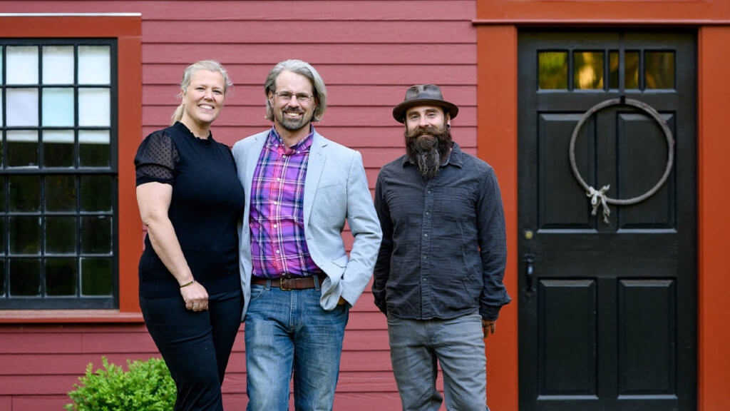 Three housing pros stand in front of a history home