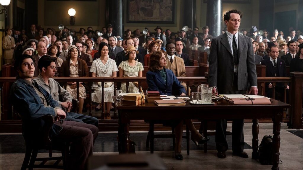 A lawyer stands in front of a courtroom in the 1930s