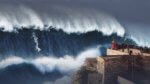 A massive wave looms over an outreach with a small lighthosue and a crowd watching a lone surfer slide down the wave.