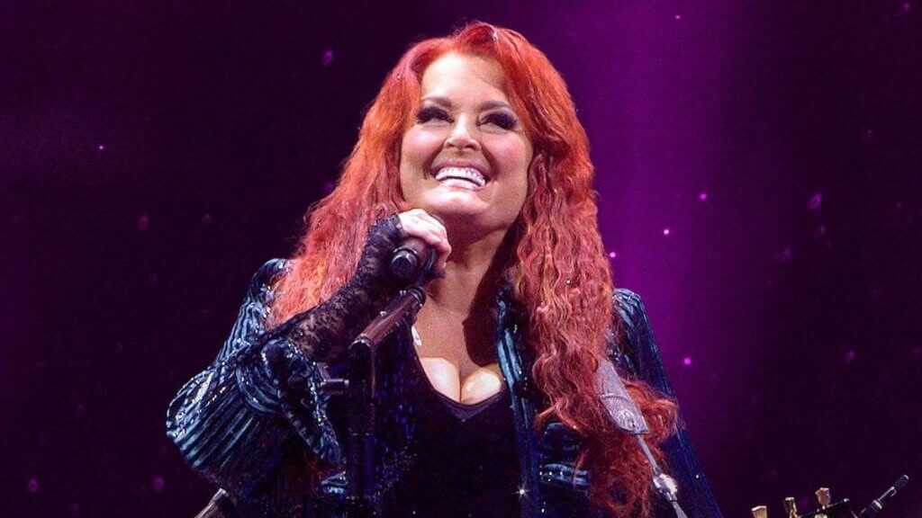 Country star Wynonna Judd holding a microphone on stage