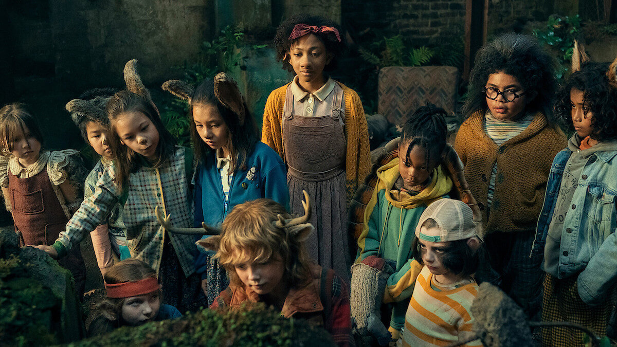 A group of animal-human hybrid children surrounding a young boy-deer.